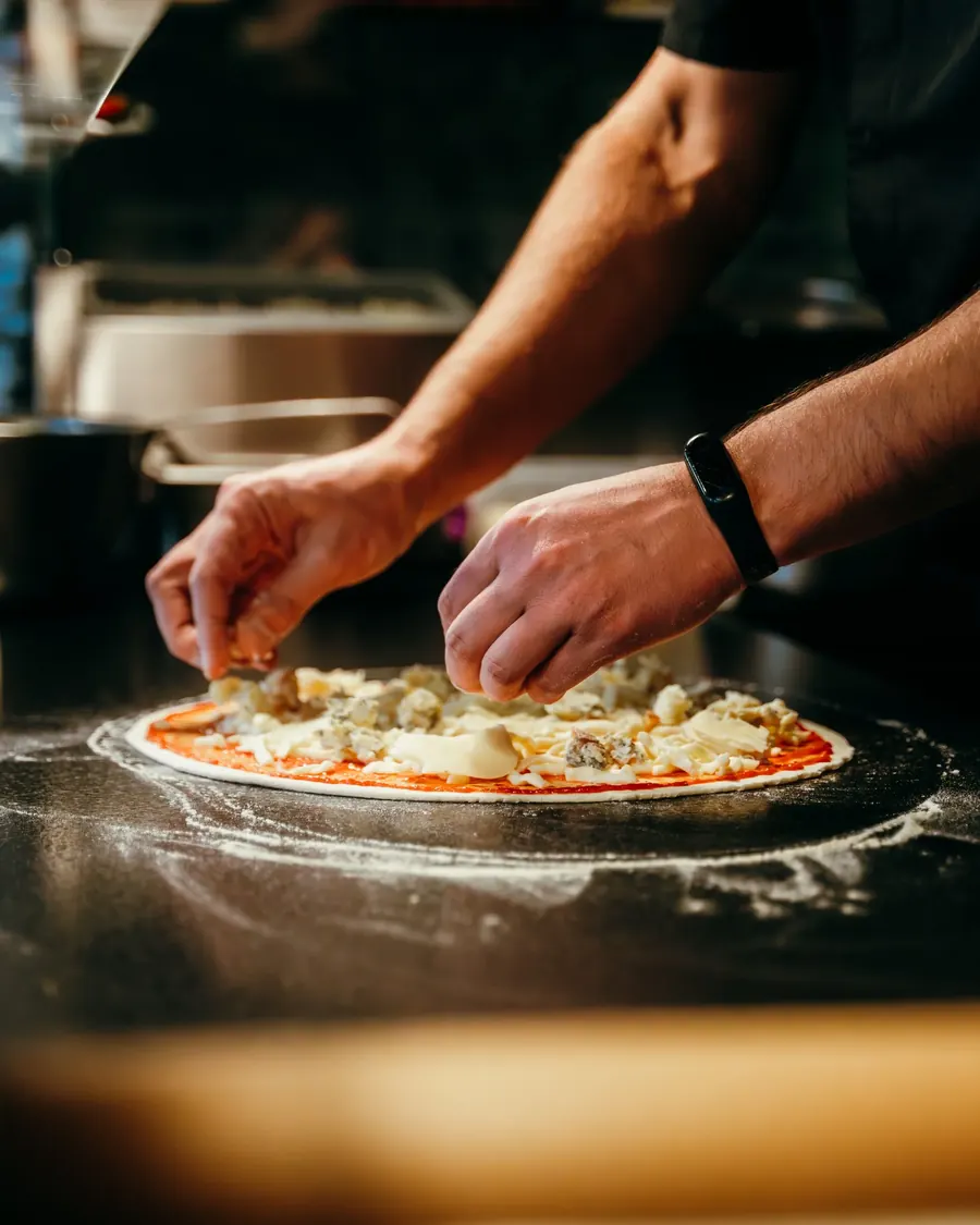 Kucharz układa składniki na pizzy w Villa Toscana Zakopane